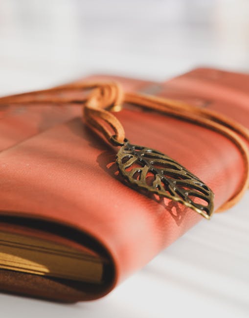Close-up image of a neatly wrapped parcel secured with a tan leather strap that has a decorative metal leaf-shaped clasp. The parcel appears to be made of sturdy, pinkish fabric or paper material. It is resting on a light-colored surface, possibly inside a home or near an entryway, with a blurred white background. This packaging technique is typical of careful packing during home relocations or moving preparations, emphasizing secure and organized packing. The image subtly highlights the importance of proper packaging and materials used in furniture transport and home packing processes, which are key components of house removals services provided by Man With a Van Bounds Green, especially in the context of avoiding damage in Victorian Bounds Green homes during a move.